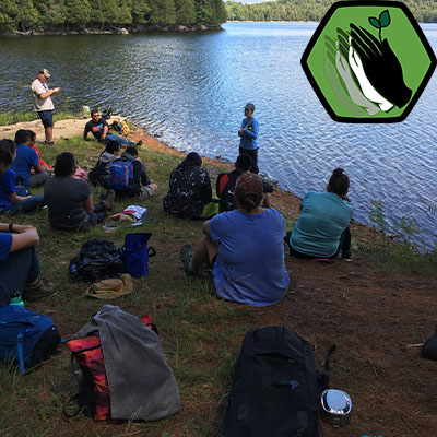 a group of people sitting on a lake shore