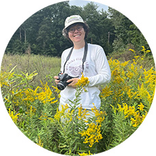 Molly Jacobson holding a camera in a meadow