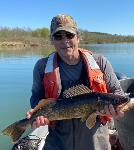 John Farrell holding a fish on a lake 