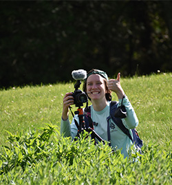 Lily Kramer in a field holding her camera