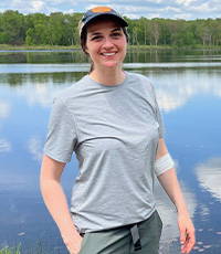 Paige Chesshire in a grey tshirt and cap standing