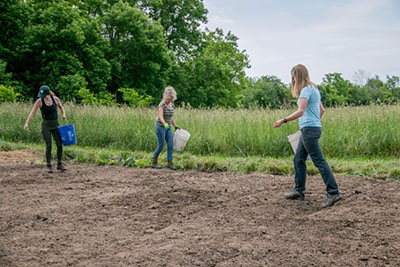graduate students and landowner seeding a meadow