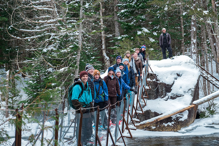 Group along a bridge outdoors in winter at the Newcomb campus.
