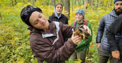 Student holding a tortoise while other students look on.