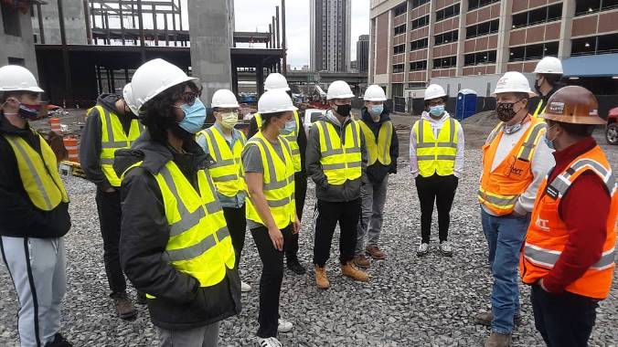 Students in hard hats gathered on a construction site.