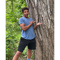 sam hopson standing next to a tree trunk