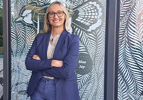 Meredith stading infront of bird murals drawn on glass door