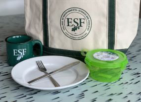 ESF branded tote bag, mug, and container with a plate, knife and fork