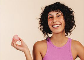 A girl n pink tank top holding a menstural cup