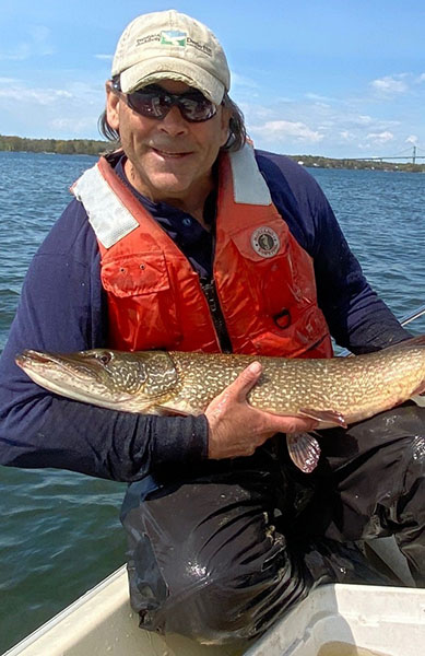 John Farrel on a boat holding a pike