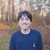 Isaac in a blue crew neck shirt smiling